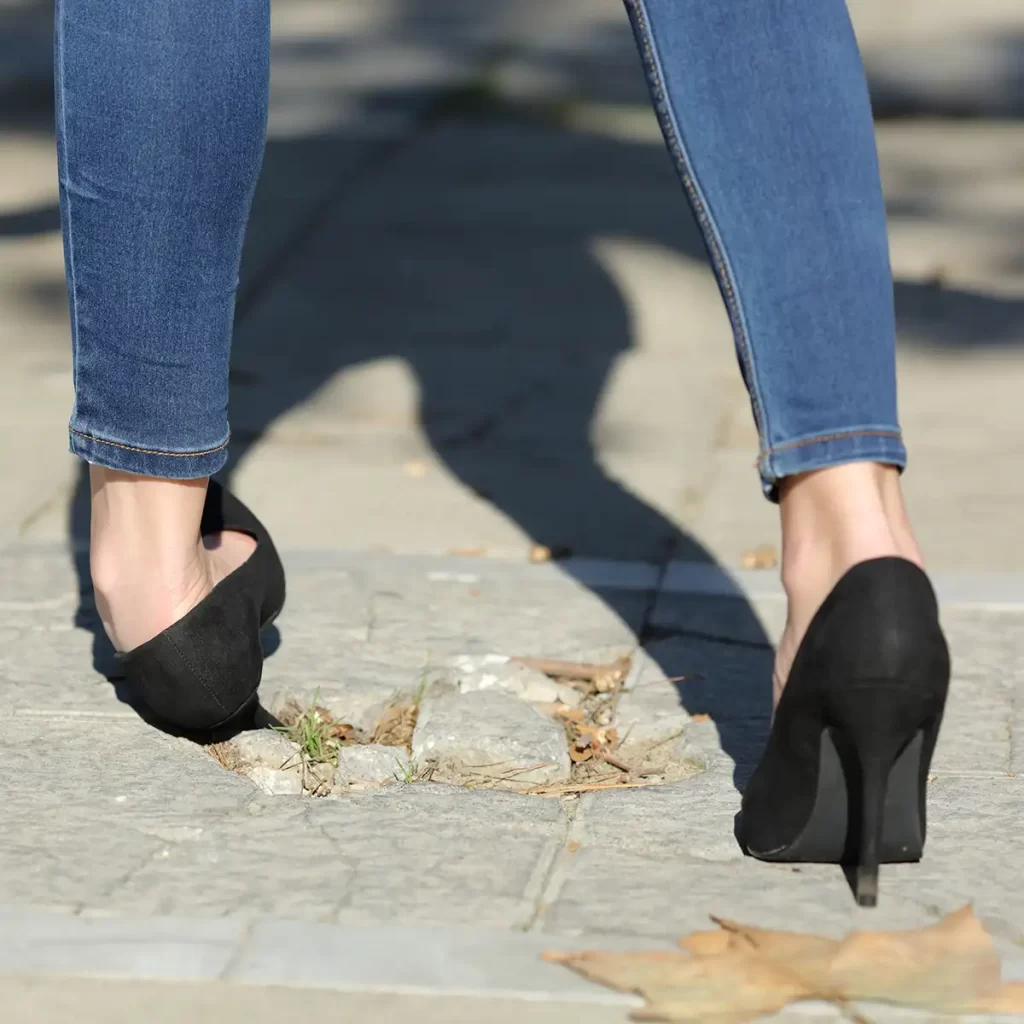 Person in high heels tripping on broken pavement